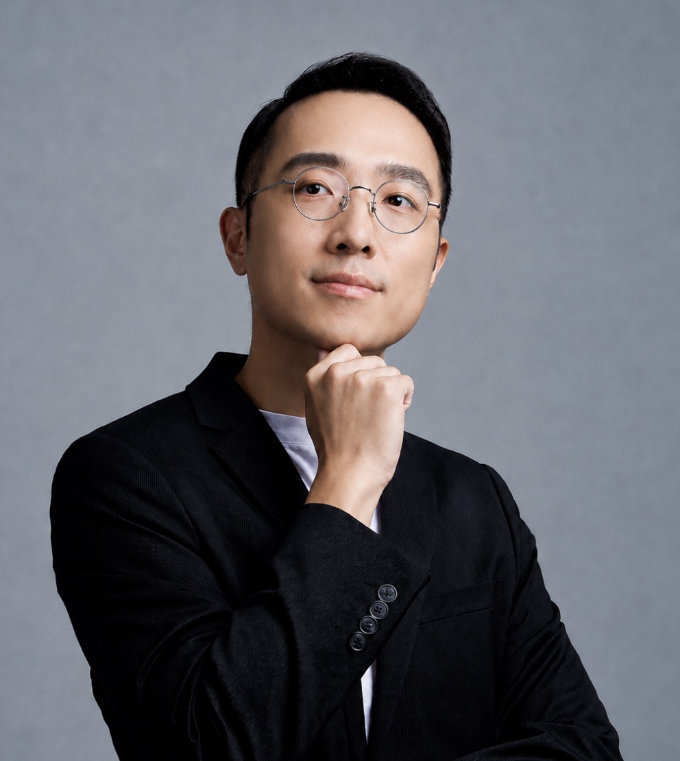 林思翰講師形象照,身穿黑色西裝、手托下巴思考